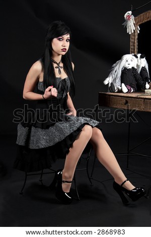 Beautiful raven haired Gothic Vampire Slayer in a black and grey dress and striking green eyes. sitting at her vanity.