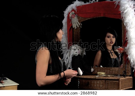 Beautiful raven haired Gothic Vampire Slayer in a black and grey dress and striking green eyes sitting at her vanity with her reflection looking back at her..