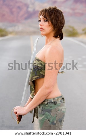 Portrait of a woman with a sword in fatigues in the desert