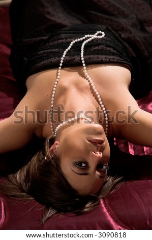 Woman dressed in an evening gown and laying on her back in bed looking back