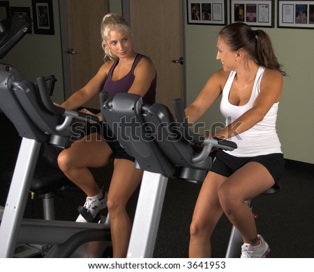 Two women during a cardio workout on an exercise bikes in the gym