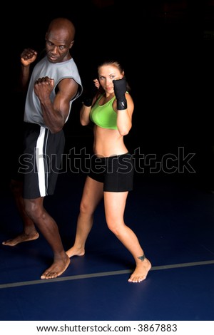 Beautiful but dangerous woman fighter working on her upper cut with her trainer in an Mixed Martial Arts gym.