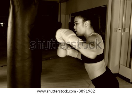 Dedicated young female fighter throwing a flurry of punches on the heavy bag Motion blur on her hands