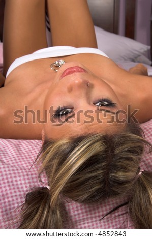 Sexy young woman laying on her back on the bed with her head hanging over the edge