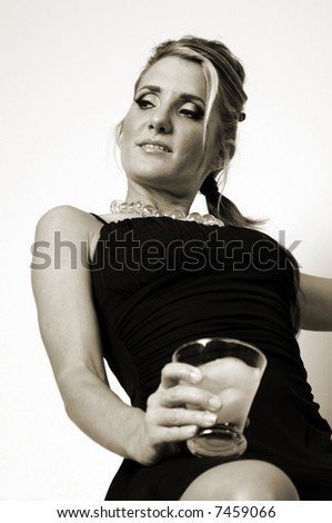 Low angle view of a young woman in a black cocktail dress with a drink sitting on a shelf in a stairway landing