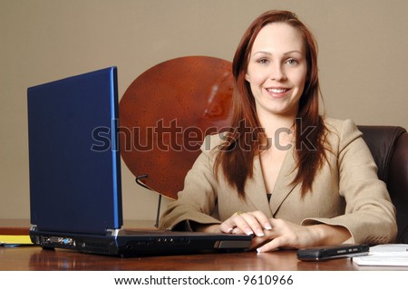 Young female executive sitting at her desk smiling and ready to serve the client
