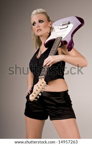 Pretty blonde in black shorts, pinstripe and lace vest and thigh high boots with a purple electric guitar over her shoulder