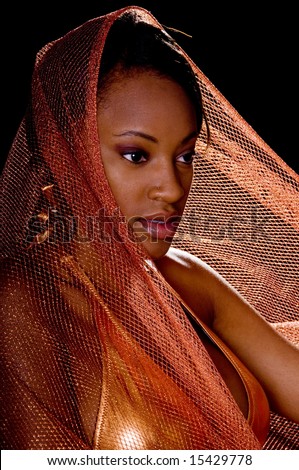 Beautiful young black woman in a gold bikini wrapped in copper mesh on a black background