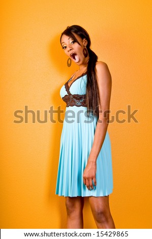 Beautiful young black woman at a party wearing a blue dress on a yellow wall