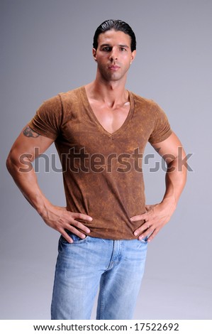 Muscular young man standing in jeans and a brown V neck tee shirt