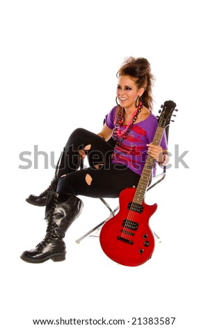Rock and roll woman with big mohawked hair dressed in purple and pink with a red electric guitar sitting in a chair