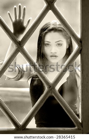 Portrait head shot of a beautiful latina standing outside a glass paned window looking in
