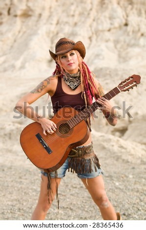 young alternative country girl standing outside and playing guitar
