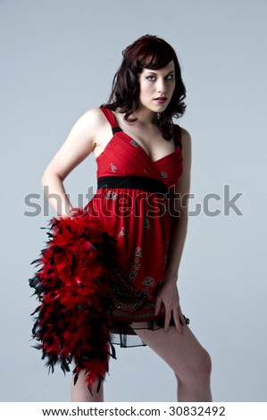 Beautiful young retro woman modeling in a red paisley print dress with a feather boa