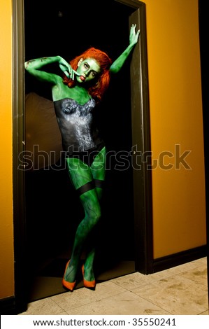 Sexy body painted female zombie standing in the doorway of a dark room just waiting on a brain