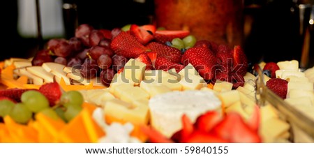 Tray of sliced cheeses and fruits, selective focus on the sliced strawberries