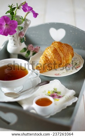 French breakfast in style Shabby chic with flowers on gray tea tray and croissant