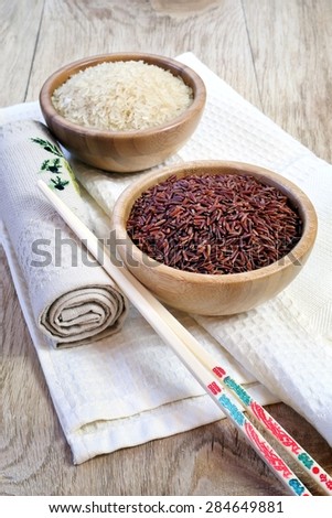 Brown and white uncooked long rice in a bamboo bowl, chopsticks