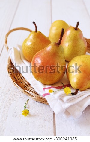 Yellow pear in wicker basket on light background