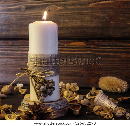 Big white candle on rustic wooden background.