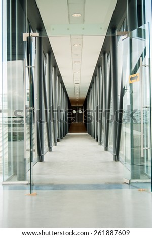 Glass corridor in airport hall with door in background