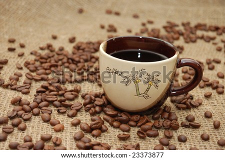 Cup with coffee. Fried beans at background