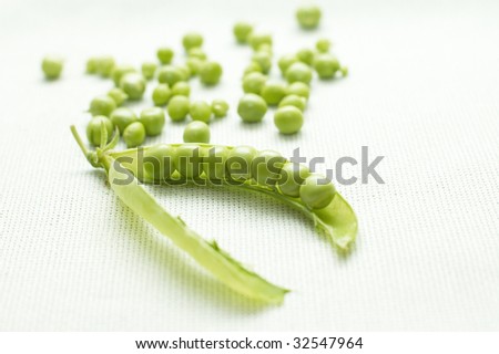 Pod of green peas and small seeds on linen background