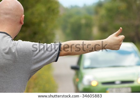 Bald-headed man hitching green car on road