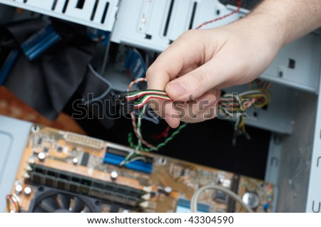 Man hand assembles computer cable into system unit