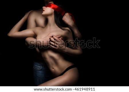 temptation topless woman and man blindfolded with silk red ribbon on black background