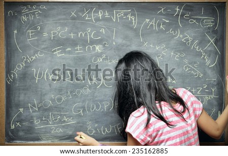 A young woman stands in front of blackboard filled with equations as if she were a genius or a teacher