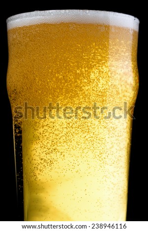 A topped off beer pint over a black background