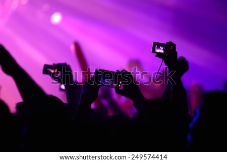 A rave and many hands with cell phones and cameras taking pictures, party, concert or rave concept