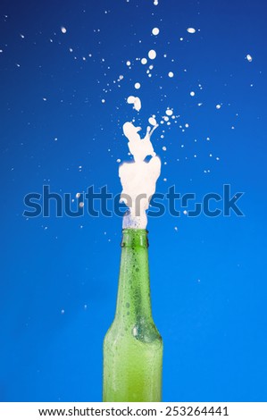 stock-photo-a-beer-bottle-bursting-up-with-foamy-liquid-over-a-blue-background-253264441.jpg