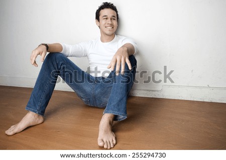 Young barefoot man in various poses on a  wooden floor next to a wall