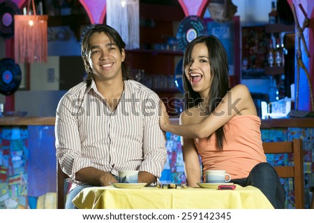 A young couple enjoys a drink in a local Mexican restaurant type of place.