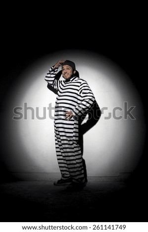 A prisoner trying to escape from prison being caught by a search light