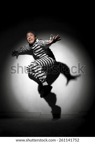A prisoner trying to escape from prison being caught by a search light