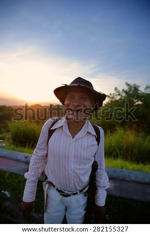 Mejicanos, San Salvador / El Salvador - July 19, 2014: A local senior man farmer with missing teeth smiles to the camera at dawn on the side of the road.