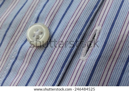 Fragment of shirt. Fabric blue stripes with a button.