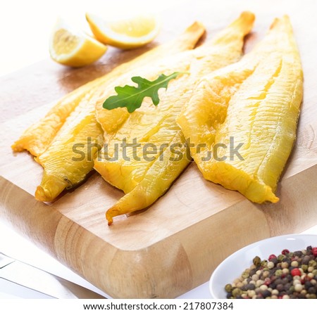 Raw Smoked Haddock on chopping board with knife, pepper and lemons