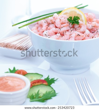 Prawn cocktail in contemporary white bowl displayed with marie rose sauce, side salad and glass of white wine