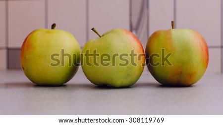 Three apple with green and red colors on the home kitchen table