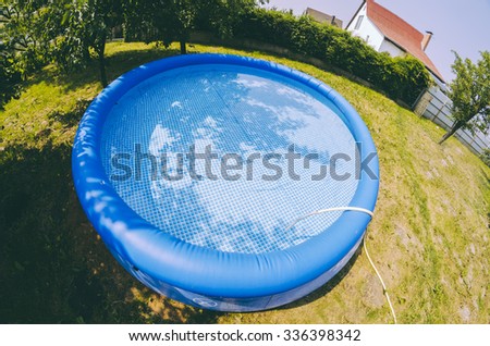 Blue inflatable pool in the village garden in summer time