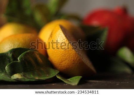 Composition with red pomegranate, leaves and orange. Selective focus on orange zest.