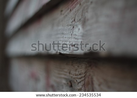 Grunge grey wooden background out of focus with perspective and selective focus on a little part of wood texture.