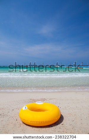 Yellow swim ring on white sand beach