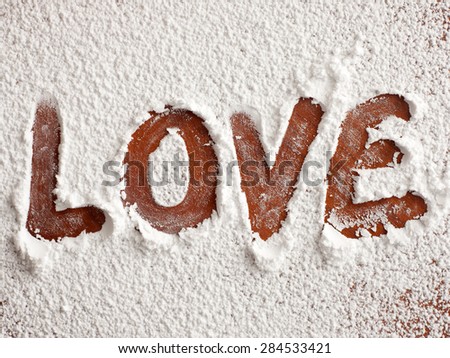 The LOVE word written over cutting board with confectioners sugar