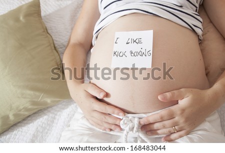 pregnant woman with post-it on the belly, funny inscription: i like kick boxing