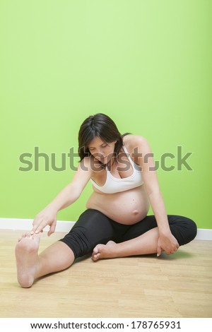 Portrait of pretty pregnant woman practicing physical exercise over white background